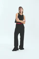 Pantalón sastrero negro de crepe con corte oversize, bolsillos laterales y tajo en la botamanga interna.