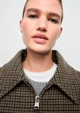 Chaqueta tipo bomber con estampa de pata de gallo en tonos marrones y verdes, cuello camisero, cierre frontal con cremallera y bajo y puños elásticos.
