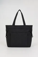 Bolso tipo shopper de nailon color negro, con asas de hombro, bolsillos frontales y cordones ajustables en los laterales con detalles metálicos.