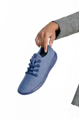 Zapatilla de diseño minimalista confeccionada en lana merino, con cordones al tono y suela de EVA. Ofrece confort térmico y un estilo atemporal.