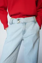 Jeans de tiro bajo con pernera recta y bajo con vuelta. Presenta bolsillos delanteros, bolsillos de plastrón en la parte trasera y cierre frontal con cremallera y botones.
