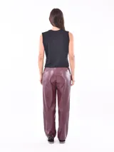 Pantalon de cuero sintetico color azul oscuro, de corte recto y tiro alto, con cintura con trabillas y cinturon incorporado con hebilla metalica dorada. Presenta bolsillos delanteros y costuras verticales decorativas.