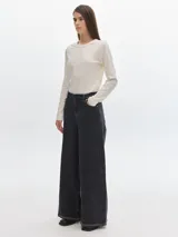 Pantalón de jean negro de tiro alto, corte wide leg y ruedo con costura a la vista.