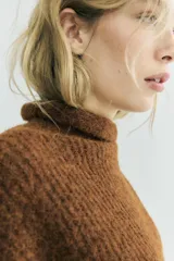 Jersey de punto con textura, cuello subido y manga larga, de corte recto y diseño clásico.