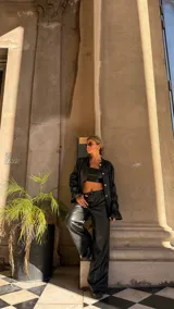 Pantalón de corte wide leg en color negro, confeccionado en material con acabado tipo cuero, de tiro medio y diseño holgado.