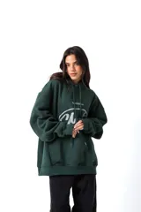 Hoodie de color verde oscuro confeccionado en friza, con capucha, cordones ajustables y bolsillo canguro. Presenta una estampa frontal blanca con el texto 'AnmeEdition' y 'CLUB' en un diseño ovalado de estilo desgastado.