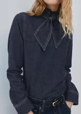 Camisa azul oscuro de denim con cuello alto y detalle de bufanda integrada en el mismo tejido.