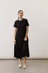 Vestido midi negro con diseño de manga corta, cuello redondo y bolsillos laterales, corte amplio y fluido.