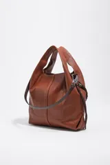 Bolso mediano de cuero marrón, tipo shopper, con detalles de cordones trenzados en la parte frontal y laterales, asa superior y logo plateado de la marca en la base.