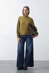 Polera de punto color marrón, con cuello alto y diseño de trenzas verticales en el frente y tejido acanalado en las mangas. Presenta mangas raglán y terminaciones acanaladas en puños y ruedo.