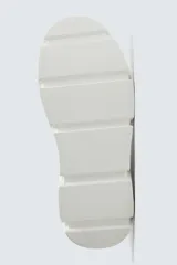 Zapatilla urbana de color blanco con diseño de suela gruesa con volumen y textura irregular. Presenta un corte superior con paneles combinados y cierre mediante cordones al tono.