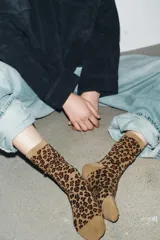 Calcetines de caña media con estampado de leopardo en tonos marrones y negros, confeccionados en tejido de algodón con acabado acanalado en el puño.