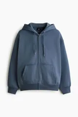 Campera con capucha de corte oversized, confeccionada en tejido de mezcla de algodón con interior suave. Presenta cierre frontal, hombros caídos, cordón ajustable en la capucha y bolsillos tipo canguro. Puños y bajo acanalados.