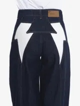 Pantalón de jean ancho (wide leg) de tiro medio, color azul oscuro, con cierre frontal de botón y cremallera, y un detalle de cierre funcional en la parte posterior.