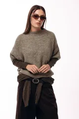 Sweater de tejido de punto grueso con silueta amplia y mangas 3/4. Presenta un diseño de calce relajado con cuello redondo y textura voluminosa.