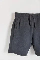 Bermuda de algodón y poliéster en color gris melange, con cintura elástica y bolsillos laterales. Presenta una etiqueta pequeña con el logo de la marca en el bolsillo trasero.