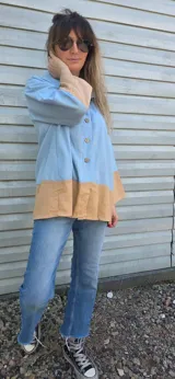 Camisa blanca de lino con mangas largas y corte holgado. Presenta un bloque de color marrón en la parte inferior.