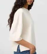 Remera de modal color crudo, con diseño minimalista, calce amplio, cuello redondo y mangas cortas amplias con hombros caídos.
