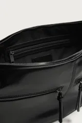 Bolso de hombro de diseño curvo en color negro, con detalle de pespuntes centrales. Cuenta con un compartimento principal con cierre de cremallera y dos bolsillos frontales con cierre. Incluye asa de hombro y bolsillo interior con cierre.