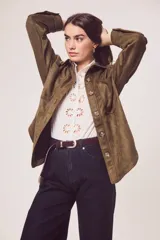 Sobrecamisa color verde militar, de corte oversize, con cuello camisero, cierre frontal con botones y bolsillos de parche en el pecho. Confeccionada en gamuza de cuero vegano.