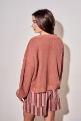 Sweater de tejido bouclé texturado color beige, con cuello redondo y mangas largas holgadas de corte amplio.