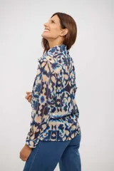 Camisa de manga larga con cuello clásico y cierre frontal de botones. Presenta un estampado abstracto en tonos azules, beige y marrón oscuro, con un corte holgado y fluido.