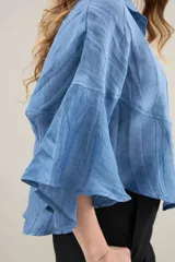 Camisa de silueta amplia y fluida color celeste, con cuello camisero clásico y mangas cortas amplias.