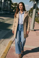 Trench impermeable de corte oversize en color camel, con diseño de doble botonadura, solapas clásicas y cinturón ajustable en la cintura.