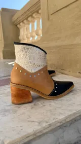 Bota tejana de cuero combinada con diseño tricolor en negro, tostado y texturizado croco metalizado plateado en la caña. Presenta punta fina, taco cuadrado de madera y detalles de tachas metálicas aplicadas.