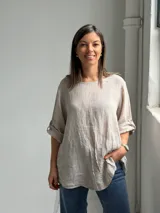 Blusa de lino color beige, de corte holgado, cuello redondo y mangas 3/4 con presillas y botones para sujetar el largo.
