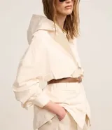 Campera oversized color beige con capucha ajustable, cierre frontal con cremallera, bolsillos cargo delanteros y puños con pliegues.