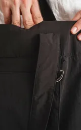 Bolso tipo tote bag de microfibra negra, con correas de hombro y cordón ajustable con tanca. Posee un bolsillo exterior con velcro y un bolsillo interior con cierre.