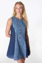 Vestido corto sin mangas, con silueta A y ruedo amplio, confeccionado en denim de dos tonos de azul. Presenta un panel central de denim celeste claro con costura central y paneles laterales de denim azul oscuro.