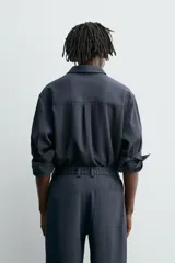 Camisa de corte relajado, color azul marino, con cuello solapa, manga larga con puños abotonados y cierre frontal de botones.