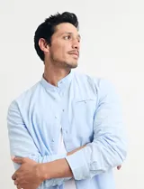 Camisa de cuello mao y manga larga, confeccionada en una mezcla de lino y algodón. Presenta un diseño de corte recto con botones en tono natural y un bolsillo pequeño en el pecho.