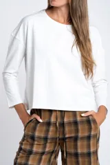 Remera de manga larga color blanco, de corte holgado y cuello redondo.