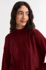 Sweater de punto color bordó con diseño de ochos, cuello redondo y mangas largas con puños acanalados.