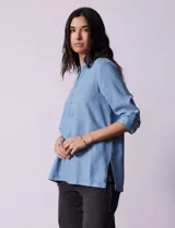 Blusa de lyocell color azul claro, con cuello camisero, escote en V con tapeta de botones y mangas largas con presilla para regular el largo.