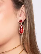 Caravanas colgantes de fiesta doradas con diseño de dos piezas con piedras rojas jaspeadas, una superior pequeña y otra inferior en forma de lágrima.