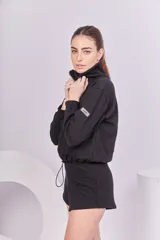 Buzo negro de rústico de algodón, con cierre frontal y reguladores en la parte inferior.