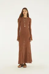 Vestido largo de punto color marrón, con diseño estampado de hojas en tono sutil, cuello redondo, mangas largas acampanadas y corte recto hasta los tobillos.