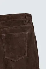 Pantalón de corte straight fit confeccionado en ante de color marrón, con diseño de cinco bolsillos y cierre frontal con cremallera y botón.