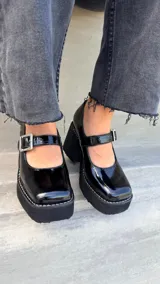 Guillermina de cuero charolado negro, con plataforma, taco ancho y tira con hebilla en el empeine.