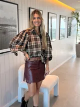 Camisa de color marrón oscuro con cuello clásico y mangas abullonadas con puños elásticos. Presenta un corte holgado y cierre frontal con botones.