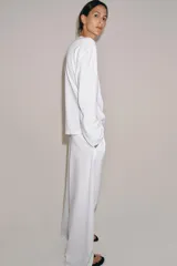 Camiseta blanca de manga larga y corte regular fit, confeccionada en mezcla de algodón y lino. Presenta cuello panadero con cierre frontal de botones y bajo recto.