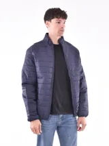 Campera puffer azul marino con cuello alto y cierre frontal. Diseño acolchado horizontal y bolsillos laterales con cierre.