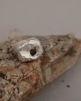 Anillo de plata 925 con diseño irregular y superficie texturizada. Presenta un orificio circular en la parte superior. Talle estándar N 15 (17 a 18 mm de diámetro).