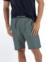 Conjunto de pijama Calvin Klein Modern Structure, compuesto por una remera azul marino de manga corta con logo estampado en el pecho y un short a rayas horizontales en tonos azul y gris con cintura elástica.