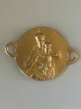 Pulsera con dije redondo dorado con diseño abstracto y cinta de terciopelo elástico color gris claro.