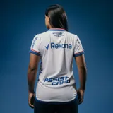 Camiseta de fútbol Umbro del Club Nacional de Football, modelo Home 2025, para mujer. Diseño blanco con detalles en azul y rojo en cuello y mangas. Incluye logo de Umbro, escudo del club y sponsor Antel en el frente.